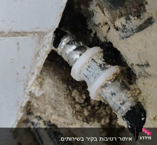 צינור מתכת עם חיבור פלסטיק בקיר חשוף